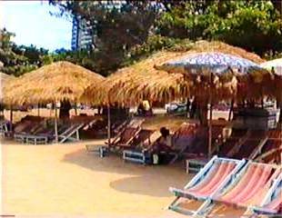Strohdächer, auch hier an der Jombien-Beach,durch Sonnenschirme großer Getränkefirmen ersetzt. 